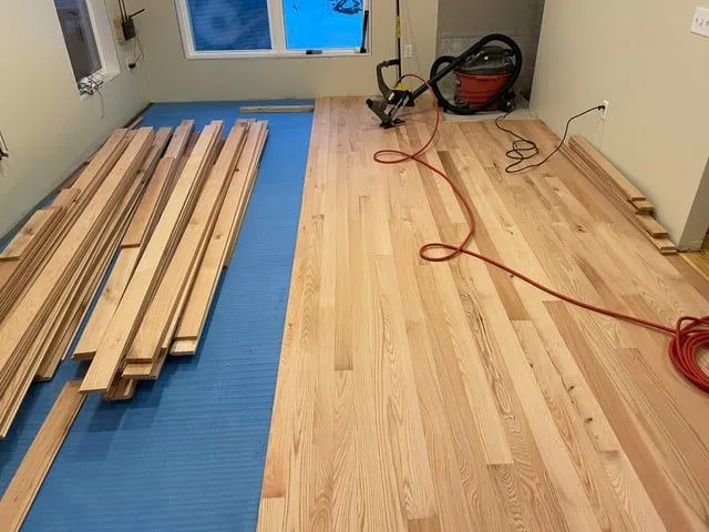 Hardwood floor installation with oak planks and underlayment