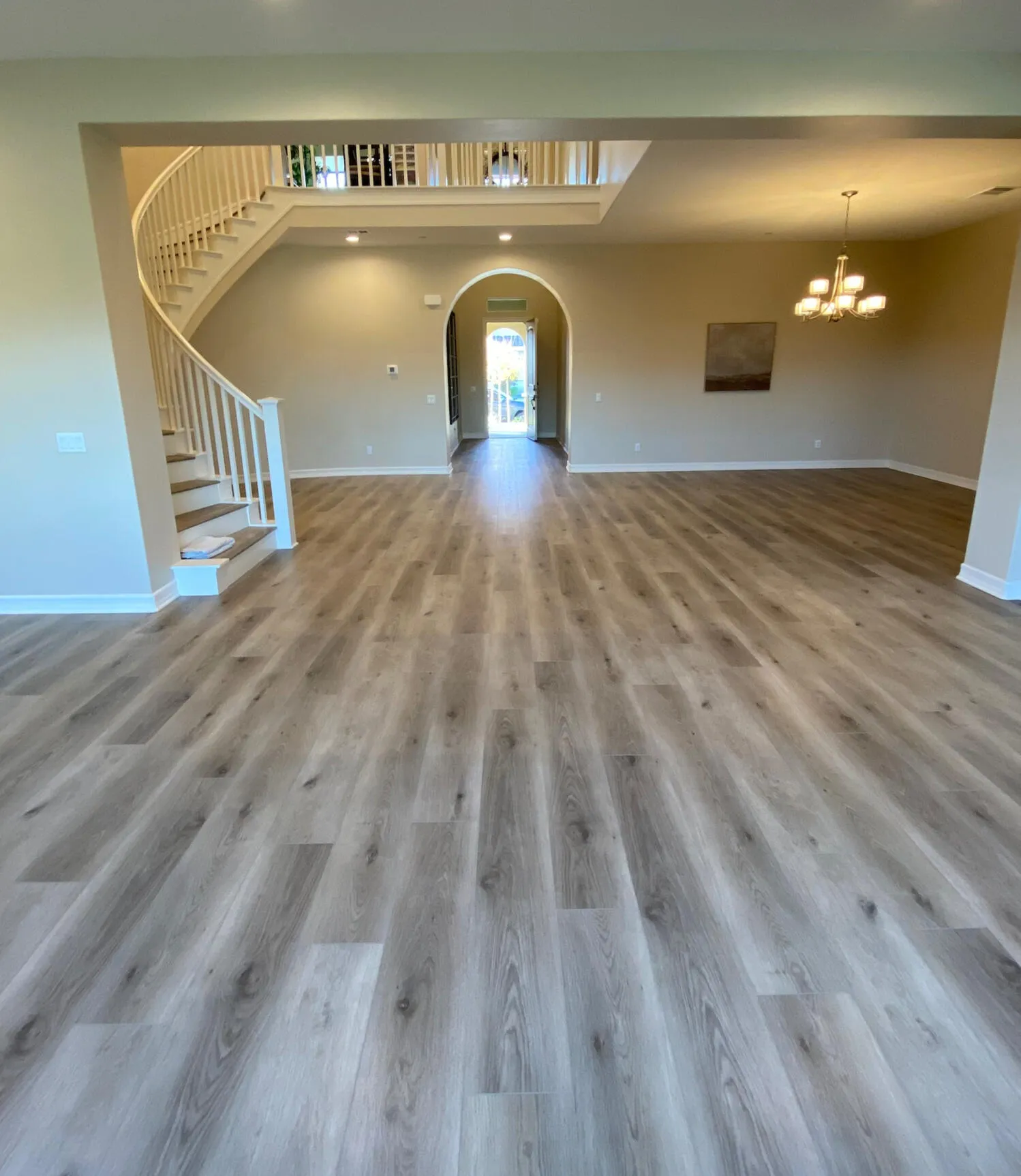 Luxury vinyl plank flooring in an open living and dining area with spiral staircase